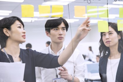 壁に付箋を貼って議論をする男女3名