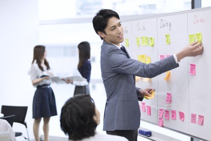 ホワイトボードに付箋を貼っているスーツ姿の若い男性